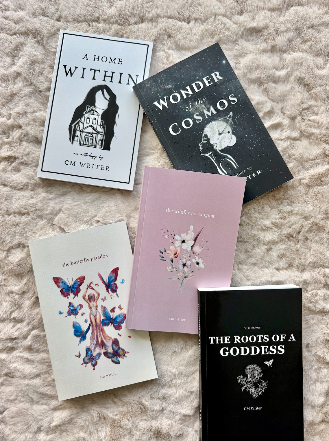 Five CM Writer poetry collections arranged on a soft blanket
